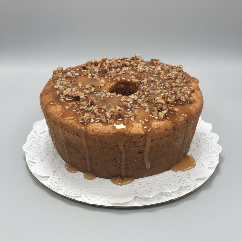 Punta Clara praline round pound cake with praline drizzle and pecan topping on a white doily against a gray background